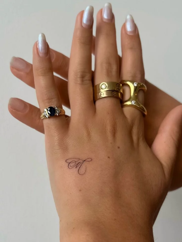 Fine line art hand initial tattoo